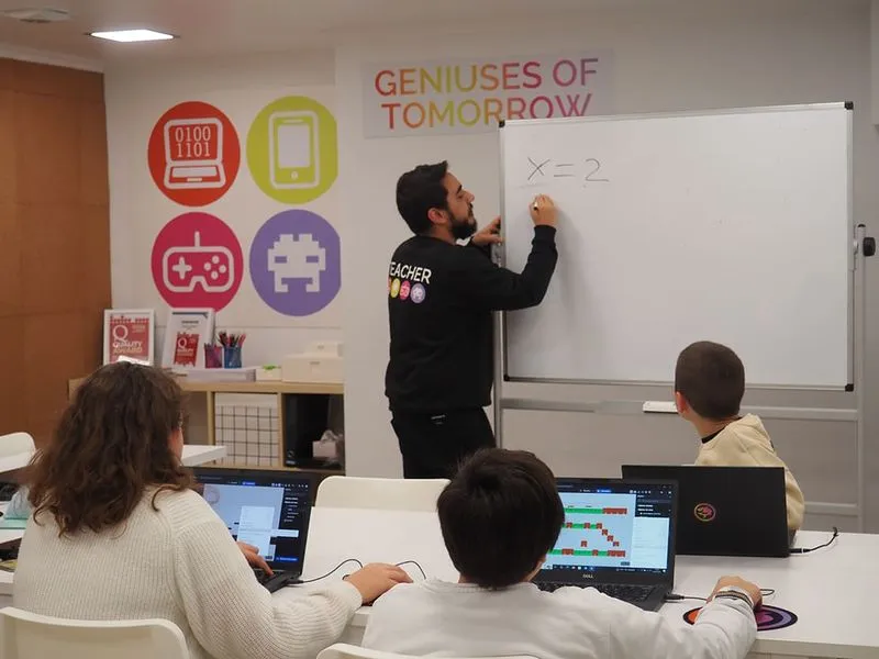Profesor SHARKCODERS en clase, con el lema Geniuses of Tomorrow